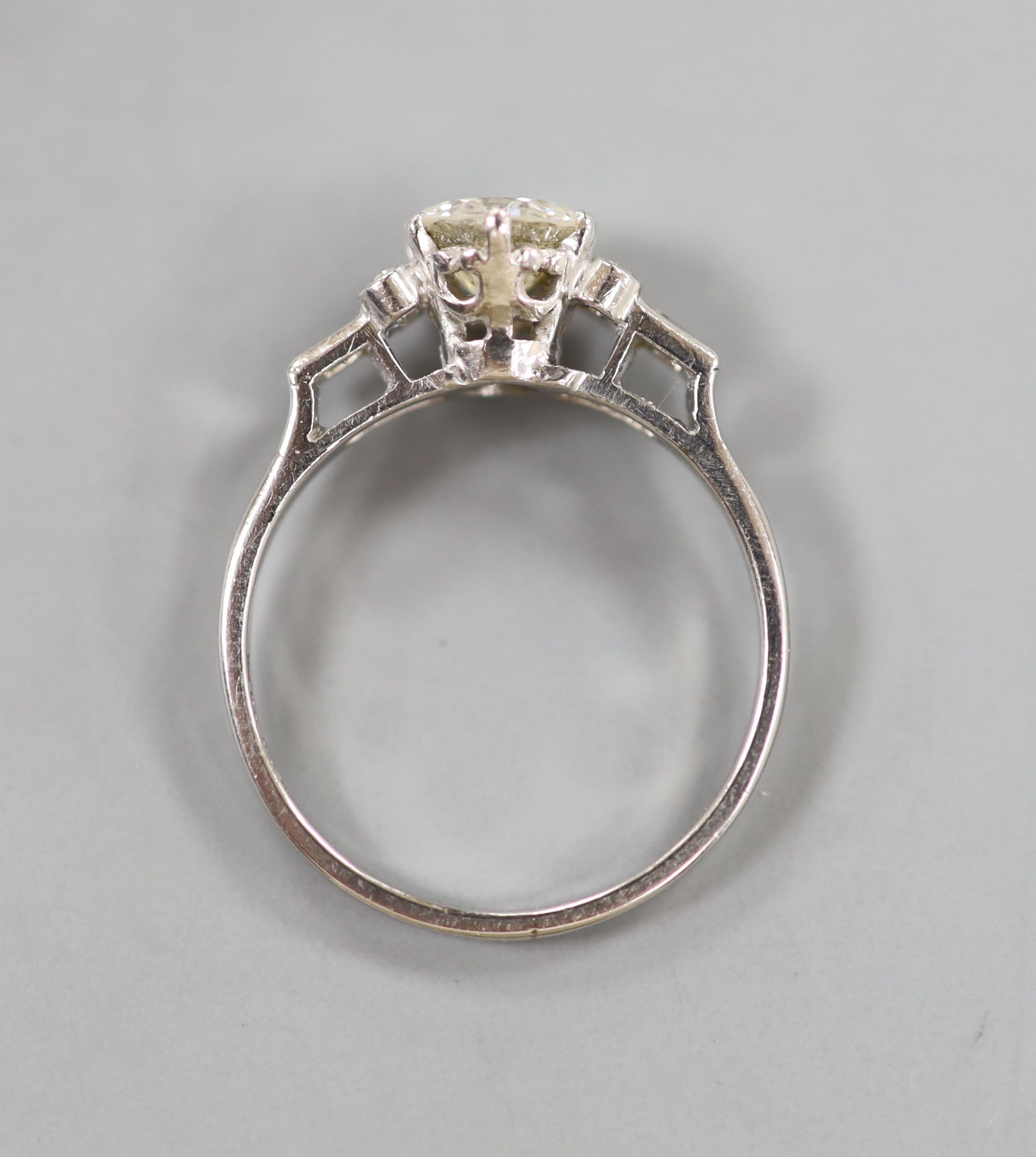 A white metal(stamped platinum) and single stone diamond ring with baguette and round cut diamond set shoulders